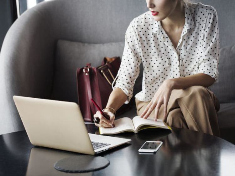 Midsection of businesswoman writing in diary at a table in a cafe