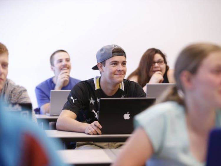 College students smile while facing ahead towards the professor