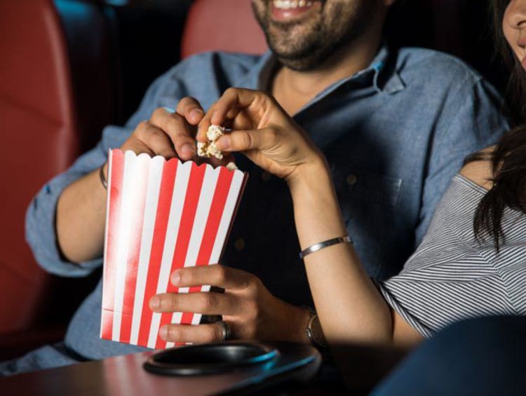 two people eating popcorn at the movies