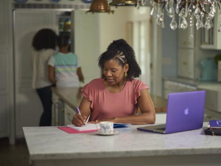 A woman taking notes at her kitchen table