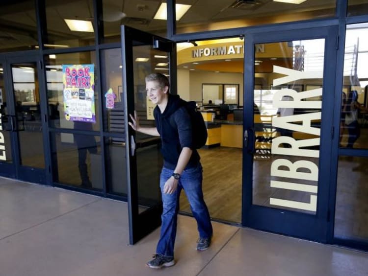 Male student walks out of library entrance