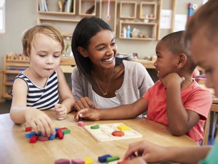 Teacher smiling helping little kids 