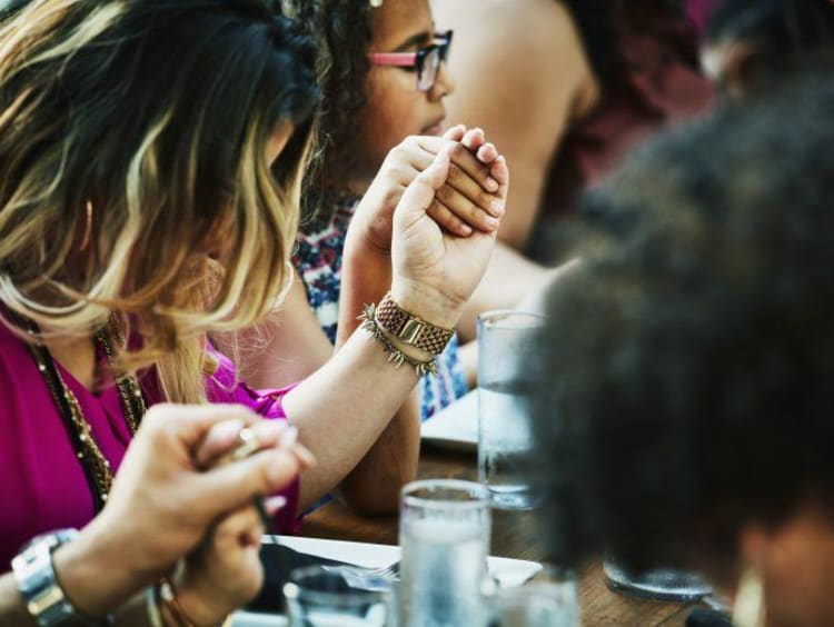 people holding hands at a table