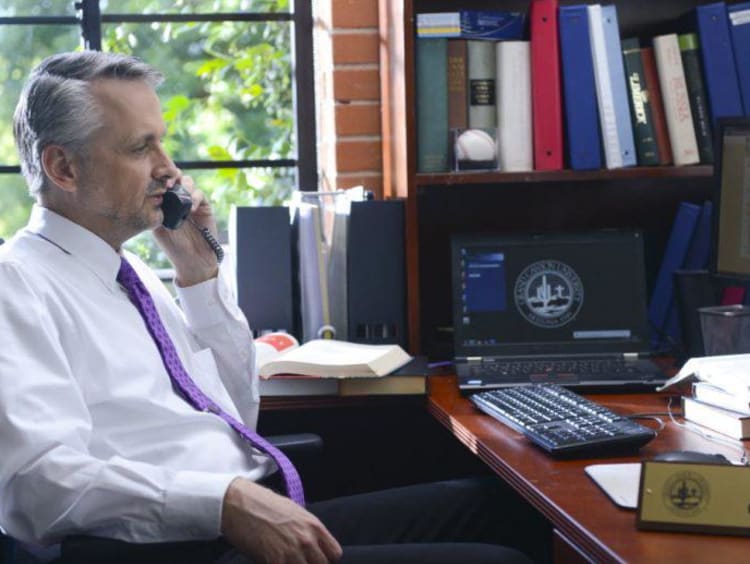 Doctoral education leader speaks on the phone in his office