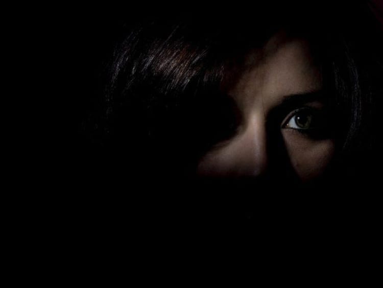 A person's face hiding in the shadows