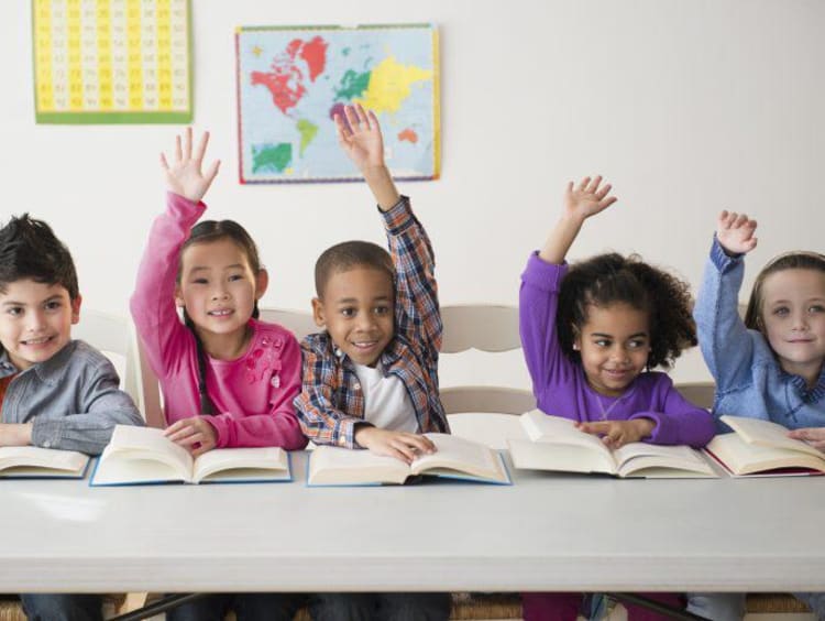 students in a row raising hands