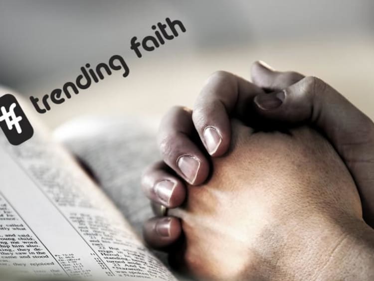 Hands clasped in prayer position on top of open bible with hashtag trending faith text on top