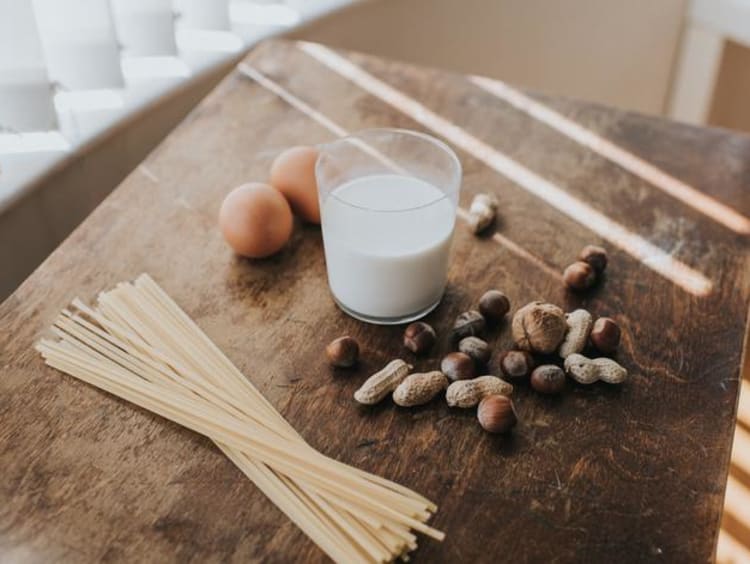 An arrangement of pasta, milk and other foods on a wood surface