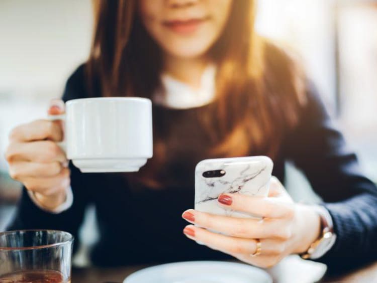 A person on their phone with coffee