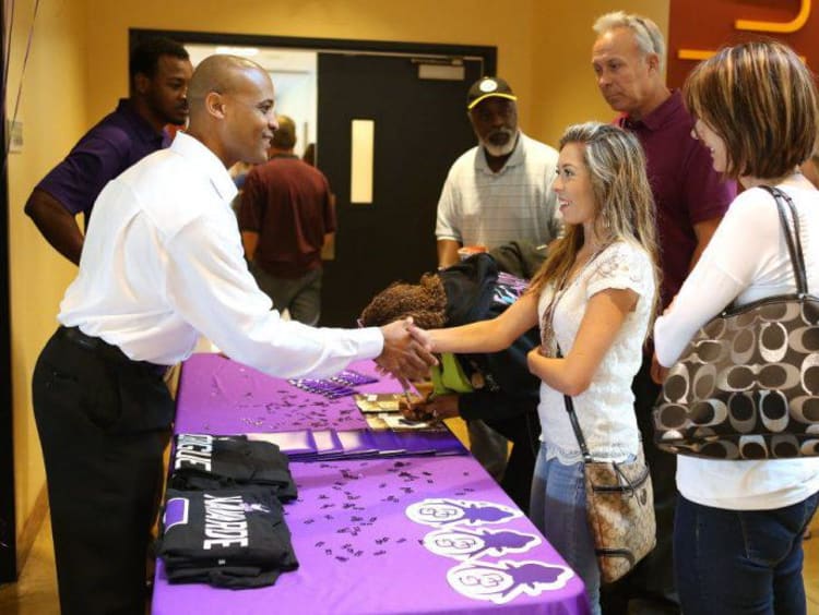 student and adult shaking hands