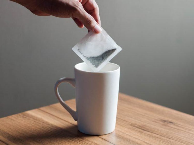 A tea bag being dipped into a cup