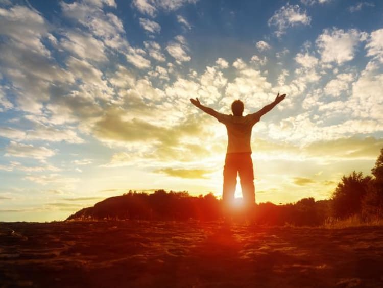 A man with his arms spread towards the sunset