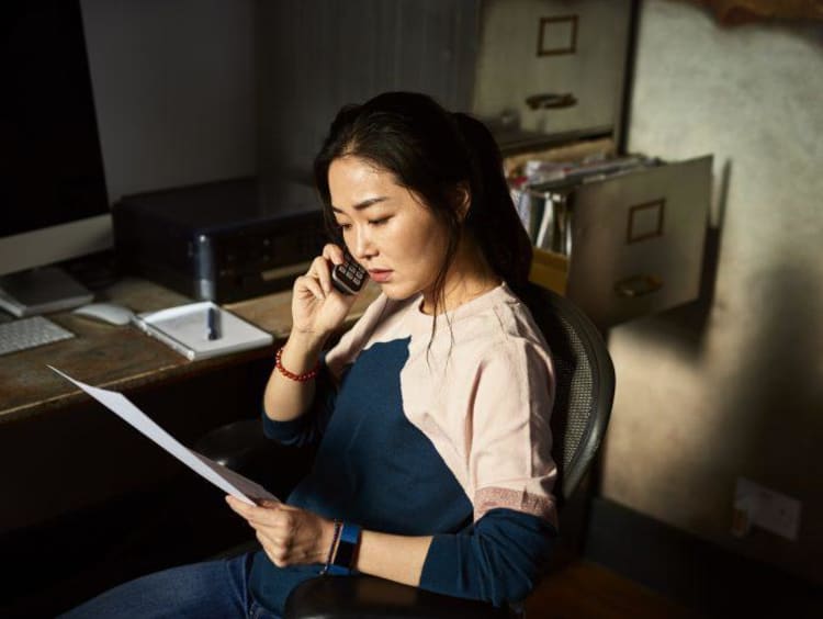 woman on the phone and reading off a paper