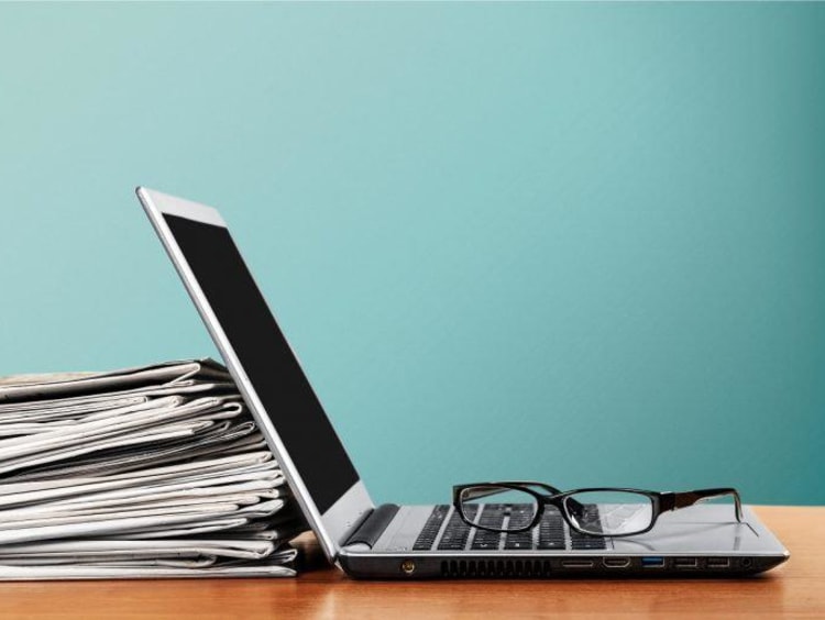 Laptop propped up on a stack of papers