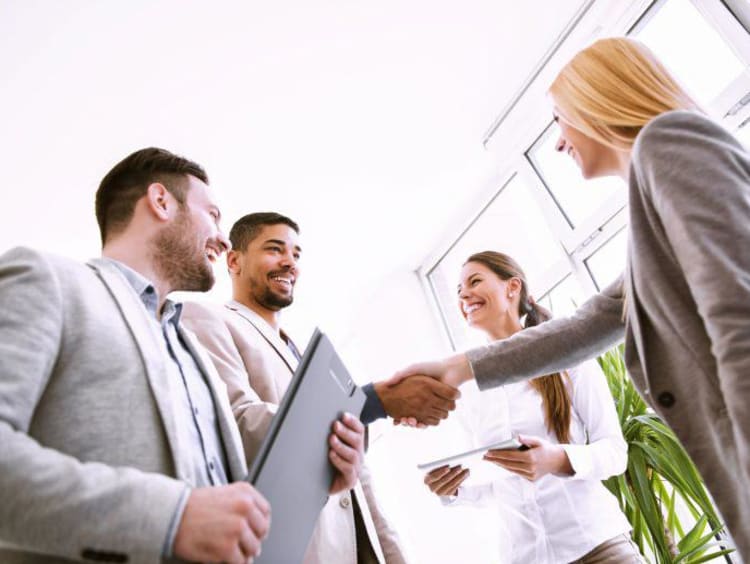 4 professionals greet each other before a business meeting