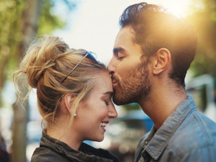 A man kissing a woman on her forehead