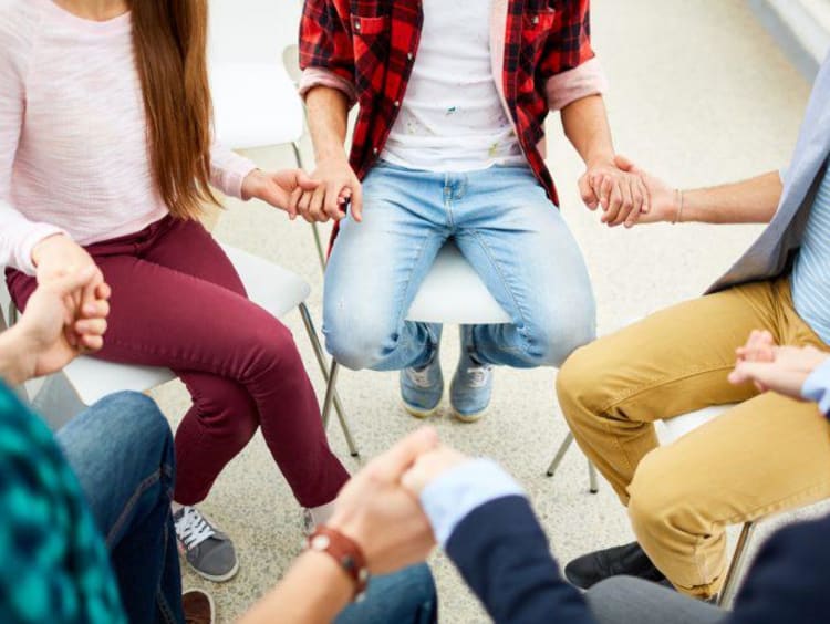 people sitting in a circle and holding hands