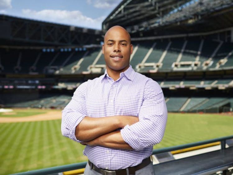 man in a dress shirt standing in front of a stadium