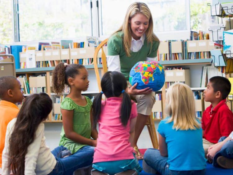 teacher showing a globe to young students