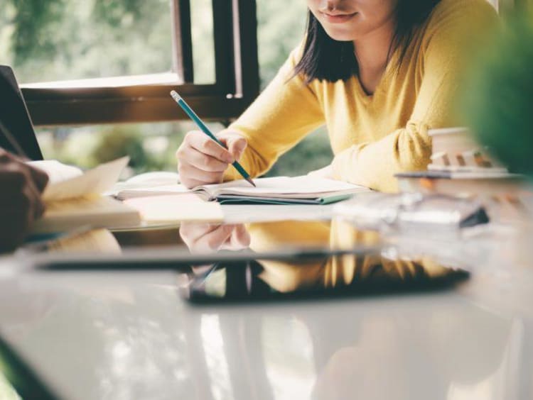 Midsection Of Woman Reading Book While Sitting At Table