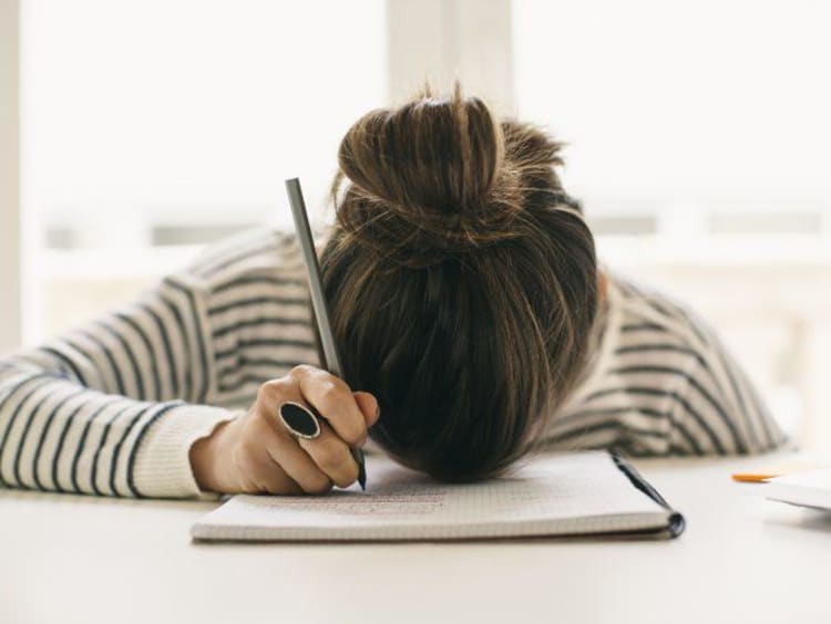 Overwhelmed student with her head on her desk