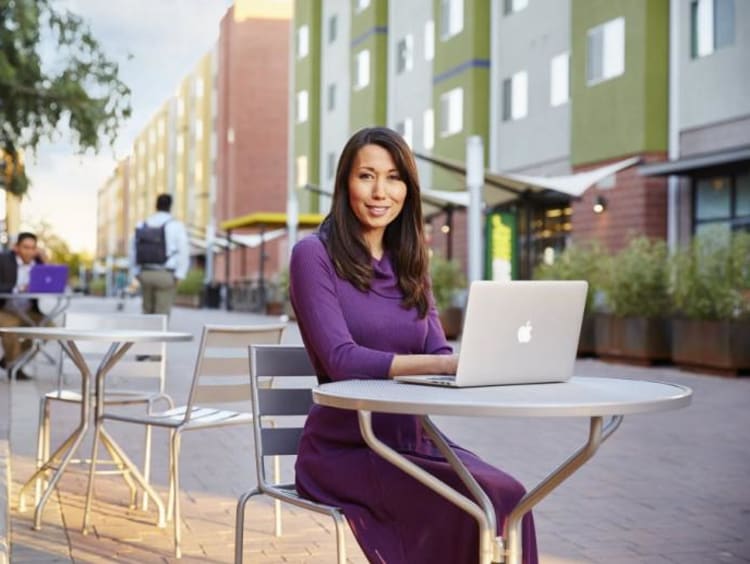 Female doctoral student working on a laptop at an outdoor table