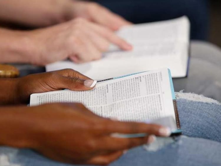 Close view of bibles opened on couples lap as they follow along