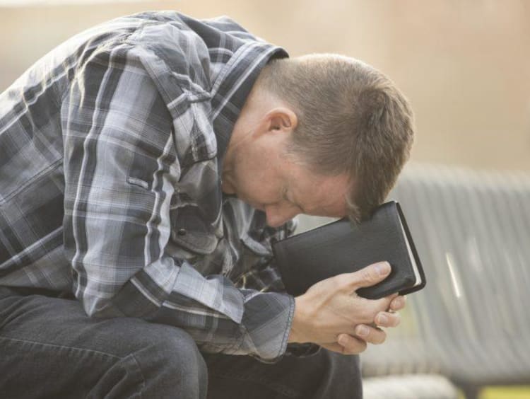 man with head down praying