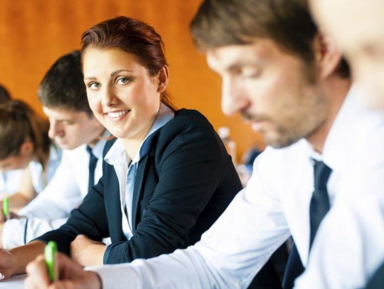 Group of professionals take assessment and girl turns head to smile