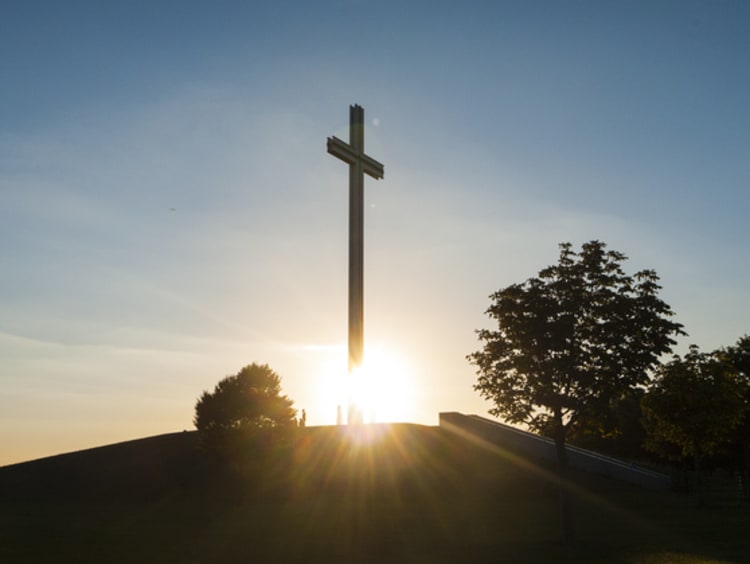 cross on a hill in front of the sun rising