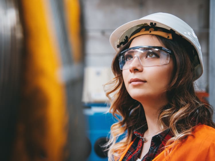 girl in hard hat and safety glasses at a construction site