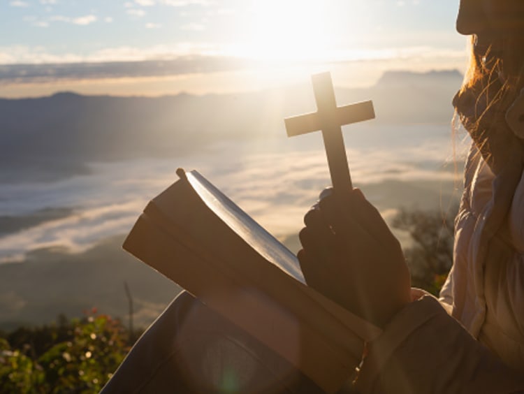 Woman praying over Gods word with a cross