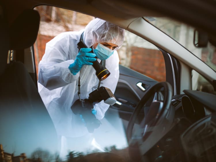 Forensic photographer taking crime scene photos of physical evidence in car