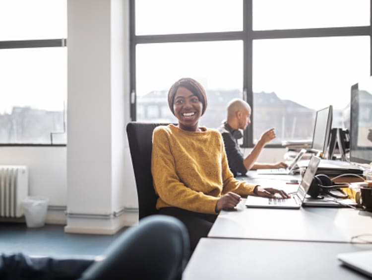 student earning tech degree smiling in front of computers