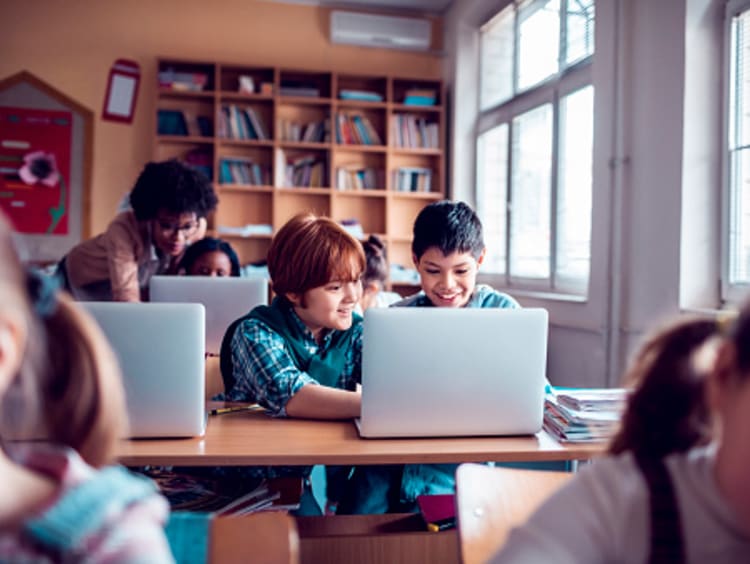 Students using laptop computers in classroom to complete work online