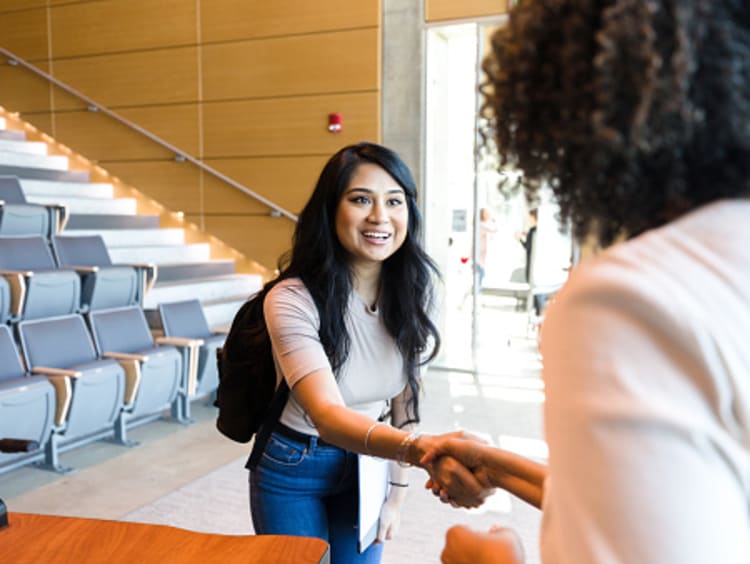 female student and teacher shaking hands when talking during office hours