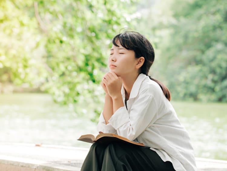 girl praying with Bible knowing Jesus loves her