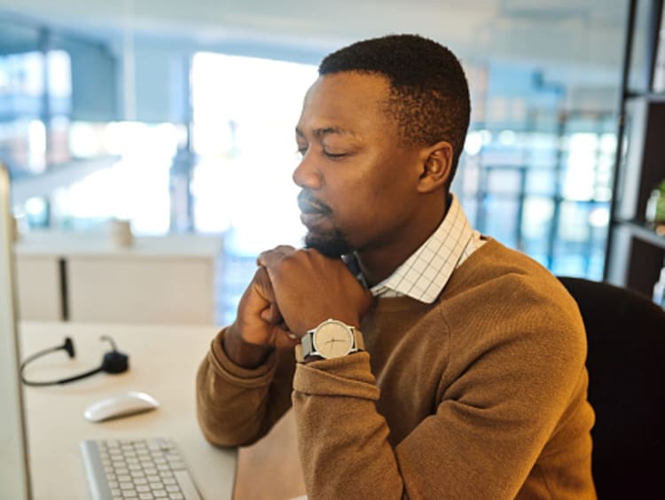 man praying at desk for God's help in walking humbly