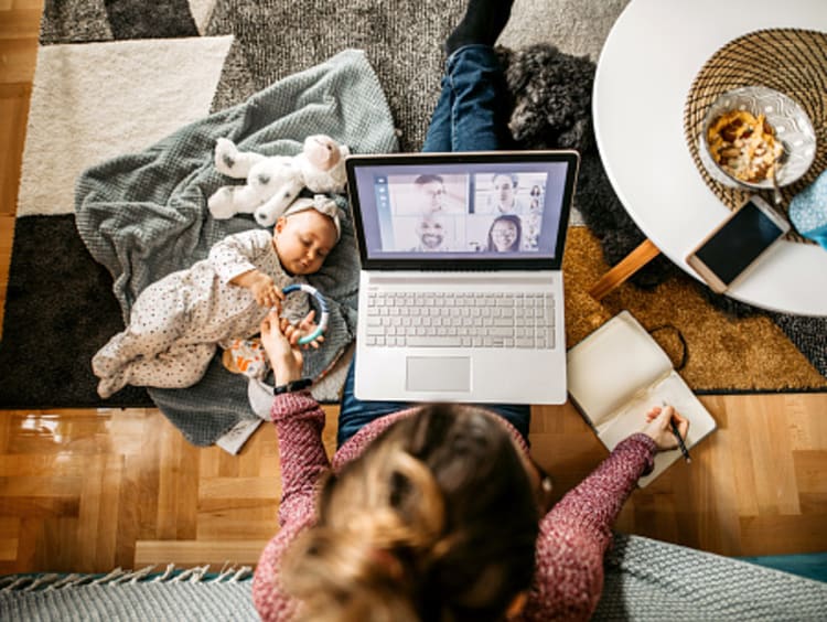 mother flourishing when life is hard by working at coffee table with baby