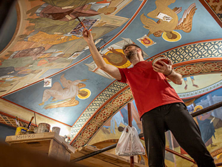 Man wearing red shirt using his gifts from God to repair Christian artwork on church ceiling