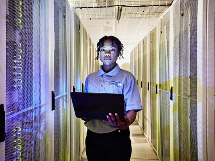 Female computer engineer programs computers in a server room