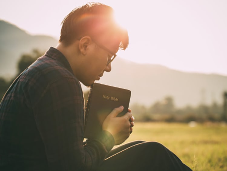 Man praying to Jesus Christ with Bible, surrendering to God