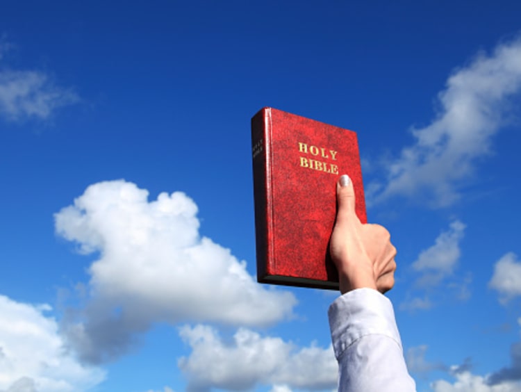 woman holding up Bible, source of Christian worldview