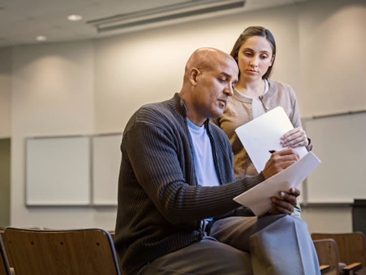 student and professor speaking and reviewing papers