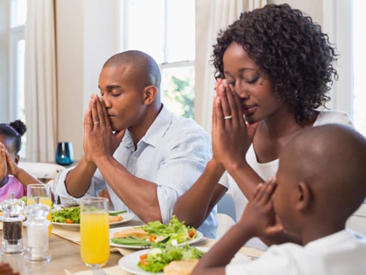 Family praying at the dinner table bearing with one another in love