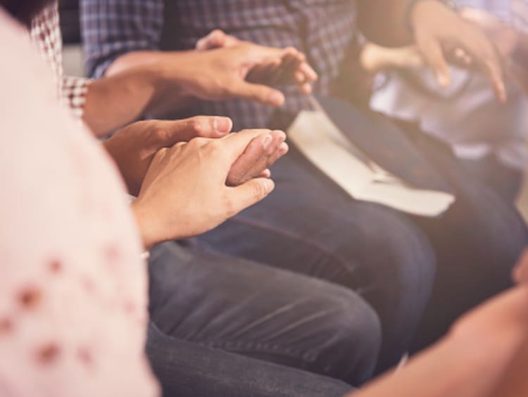 Christians encouraging one another by holding hands and praying