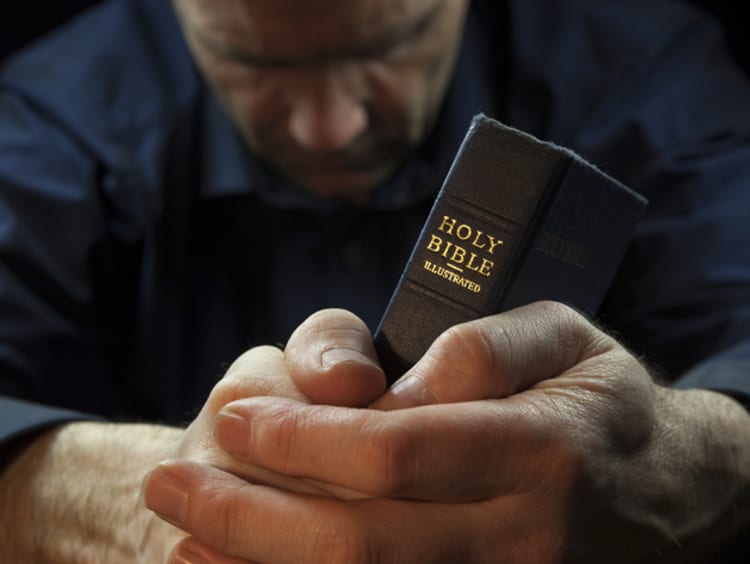 a man holding the bible between his hands and praying