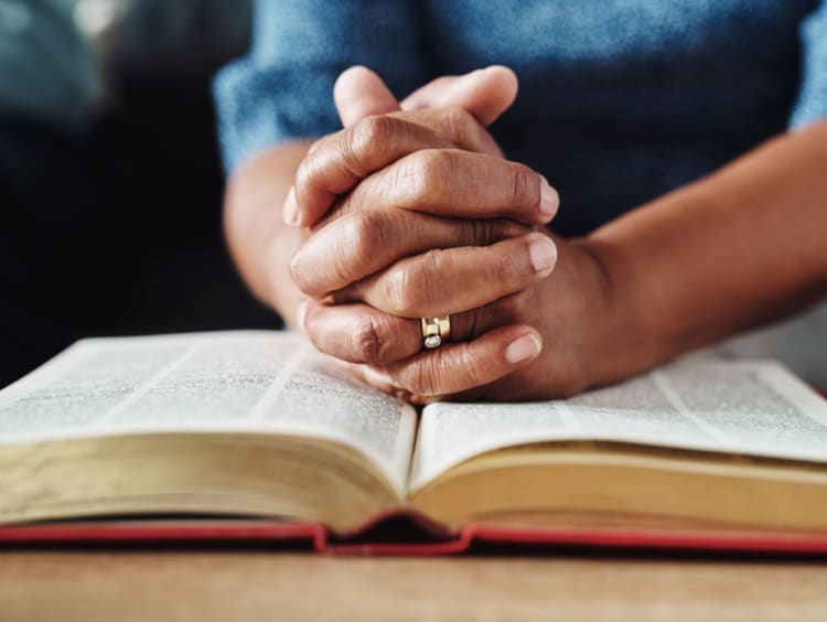 Hands praying over Bible