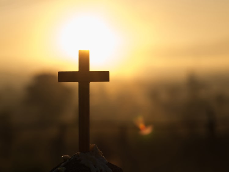 cross being held up to the sun by someone