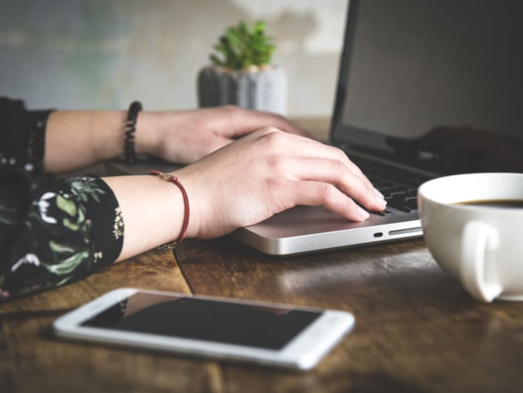 hands of copywriter typing on laptop at desk